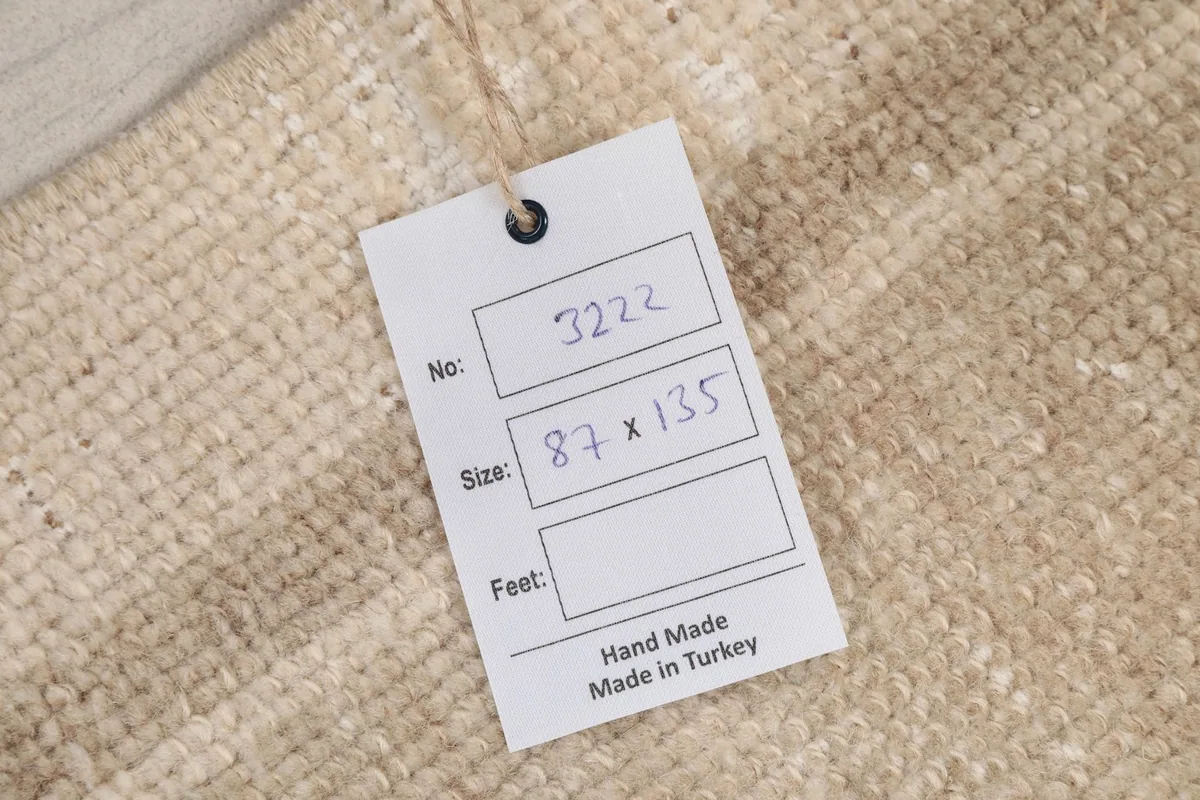 Close-up of the rug's label showing its dimensions in centimeters and origin.