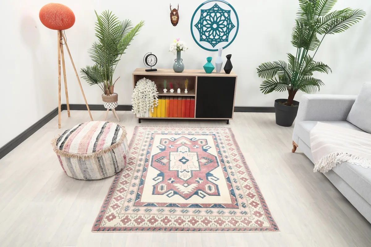Vintage Anatolian rug displayed in a living room setting with a light grey sofa and pouf