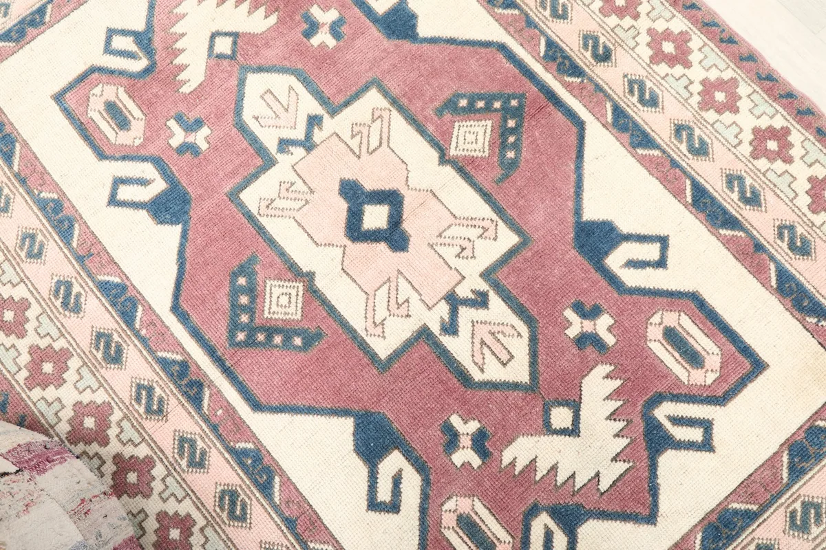 Close-up of the central geometric medallion and surrounding patterns in rose and navy