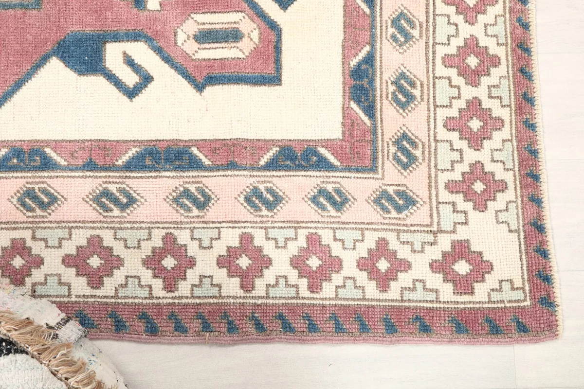 Detail of the outer border of the vintage rug, showing rose and ivory geometric motifs