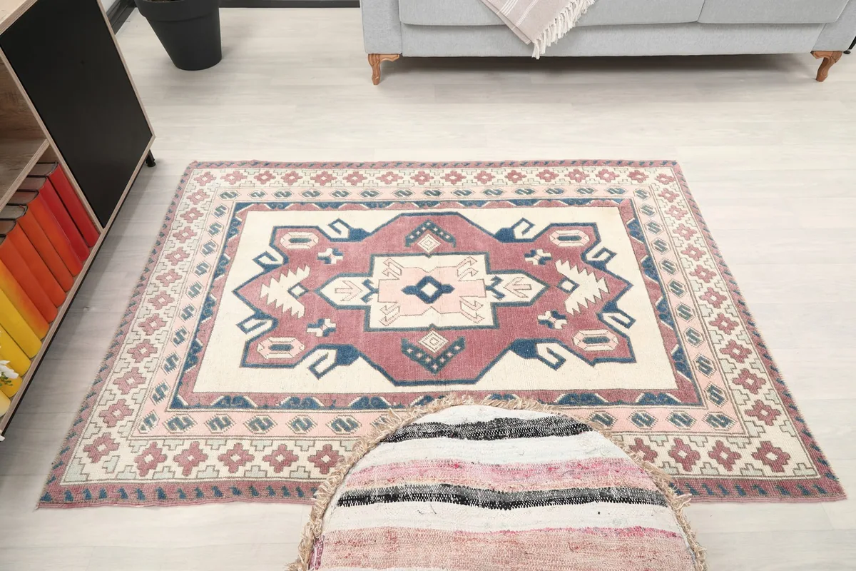 Overhead shot of the small area rug on the floor, with a pouf partially in view
