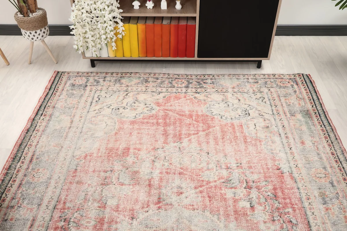 Overhead angle of the vintage rose and gray rug, showcasing its distressed character in a room