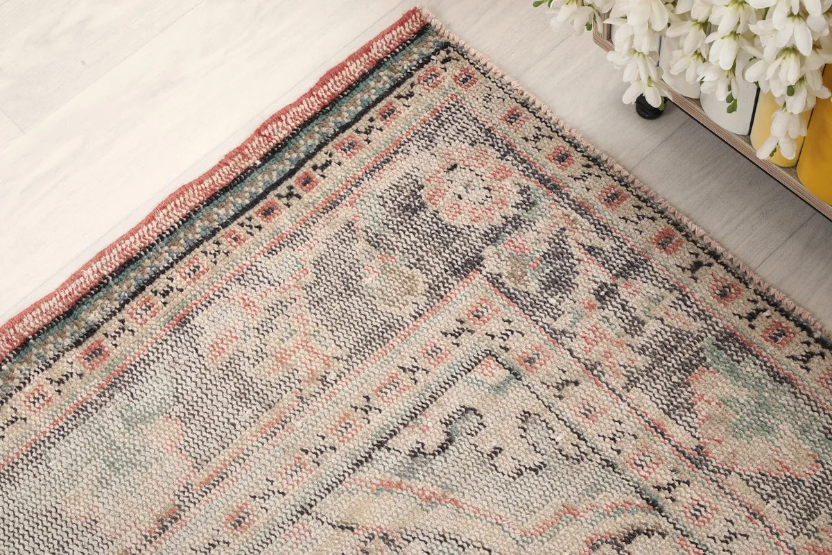 Corner detail of the rug's border, showing the blend of gray, navy, and rose colors