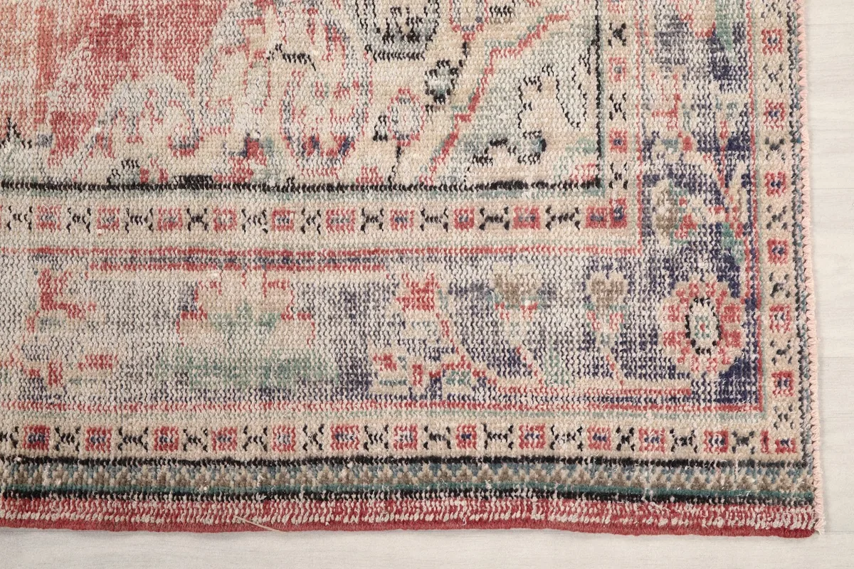 Detail of the gray and navy border with geometric patterns and subtle rose accents on the rug