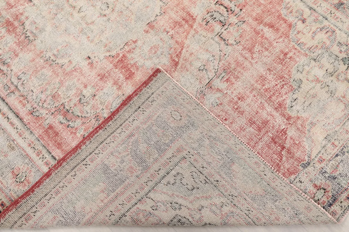 View of the rug folded back to reveal the cotton foundation and the reverse side of the wool knots