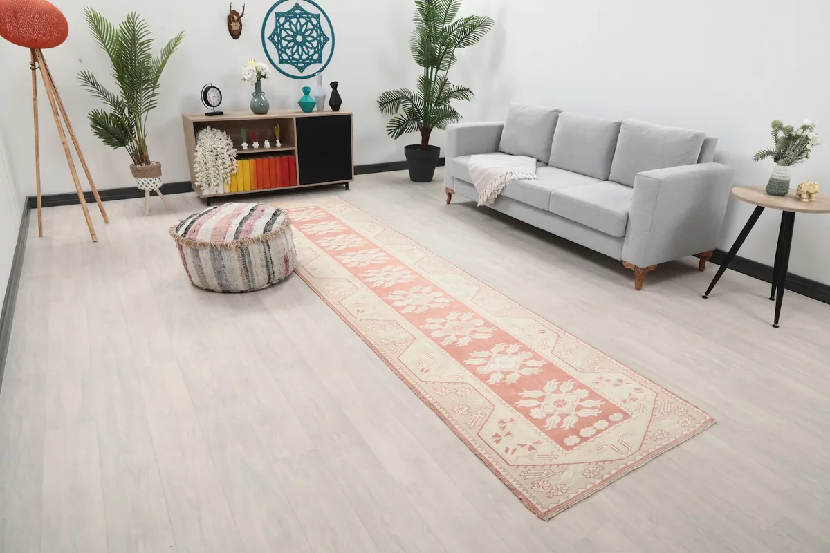 Overhead view of the rose and ivory runner rug in a room with a sofa and pouf.