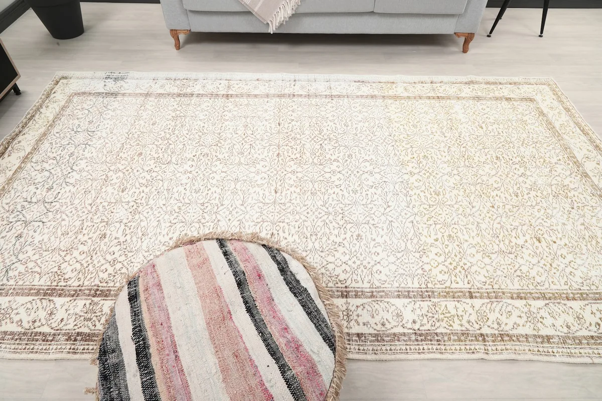 Overhead view of the rug in a room, showing its full length and width with a pouf in foreground