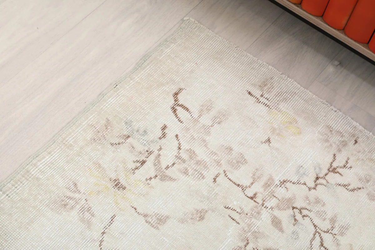 Detailed view of the rug's floral motif, highlighting the muted colors and the vintage character of the wool.