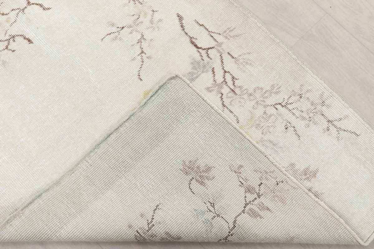 Corner of the rug folded back to reveal the cotton foundation and the reverse side of the hand-knotted construction.