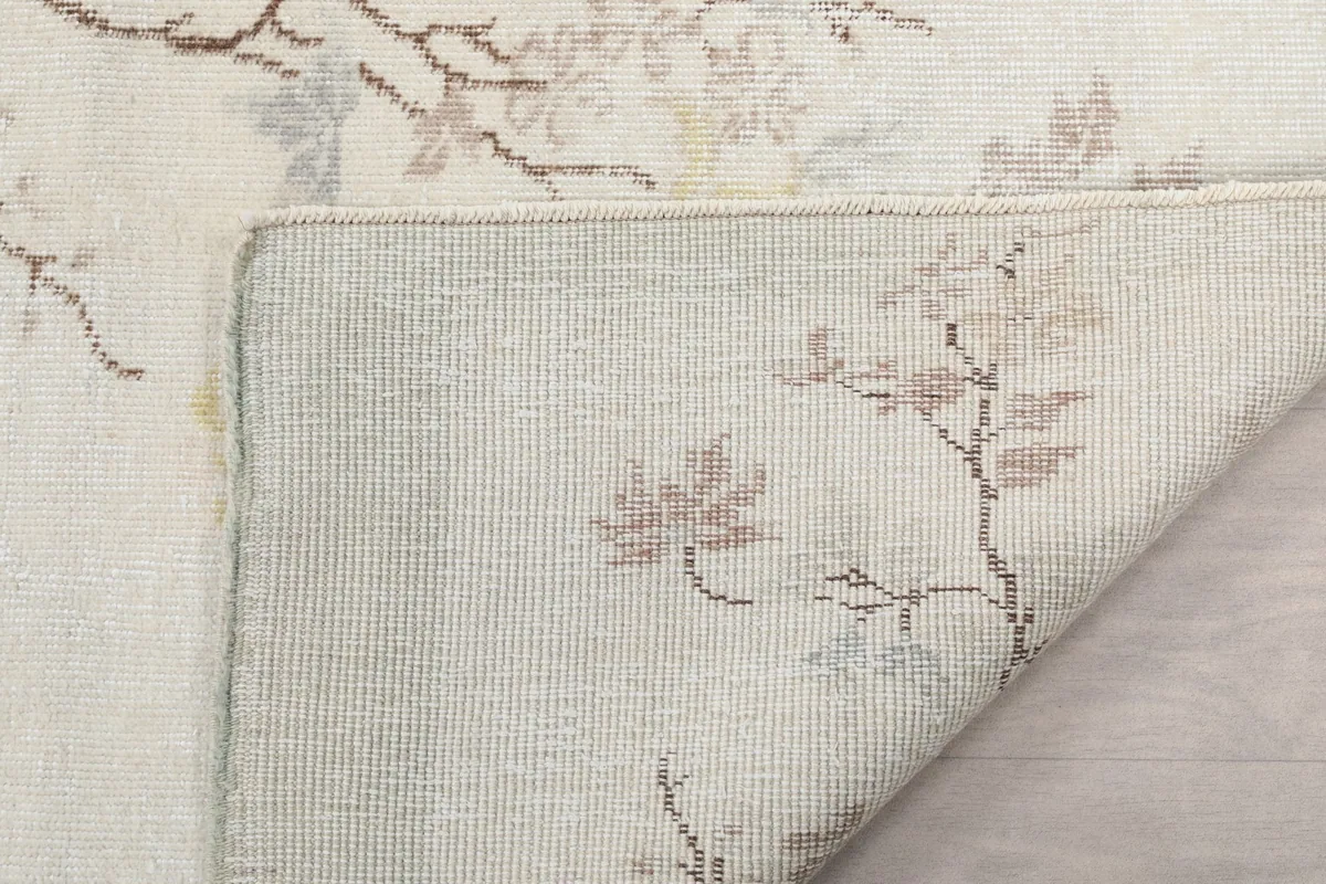 Close-up of the rug's underside, showing the tightly woven cotton foundation and the back of the wool knots.