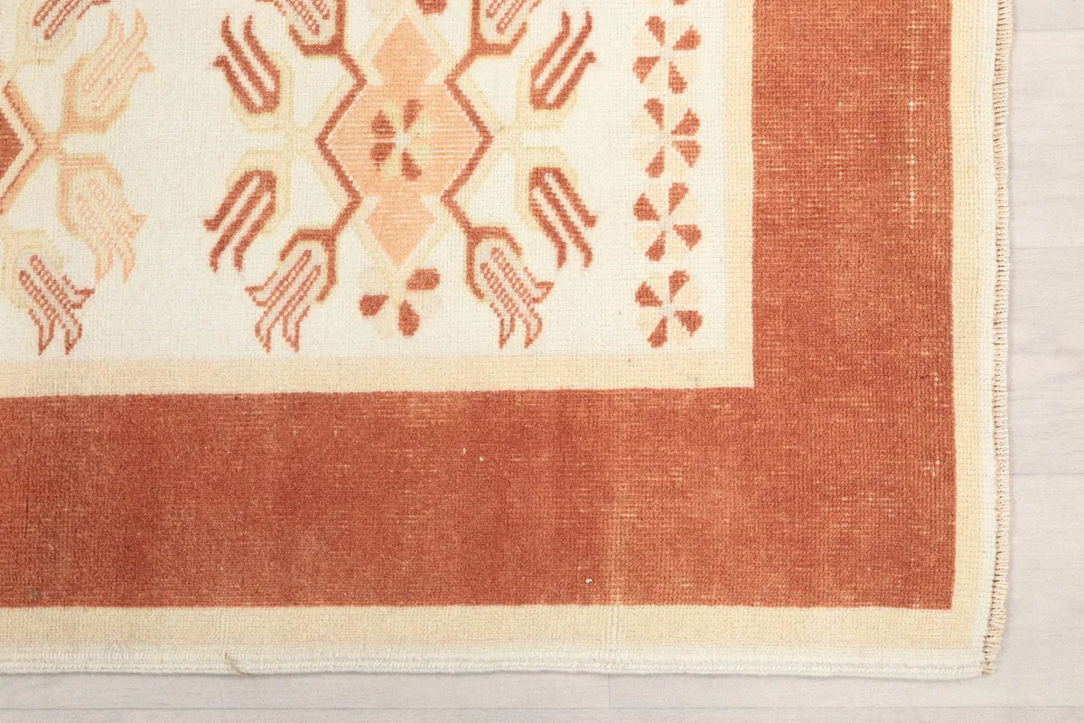 Corner detail of the rust border and ivory field, showing edge finishing