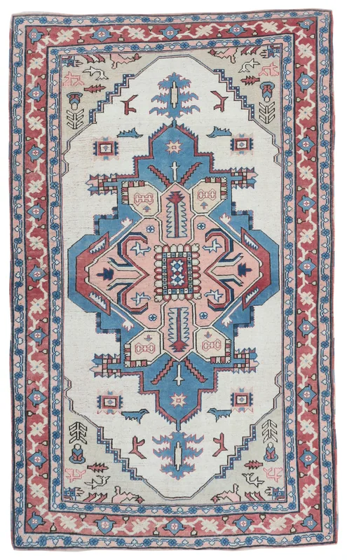 Full overhead view of the vintage Anatolian rug with ivory field, blue and pink geometric medallion, and red border.