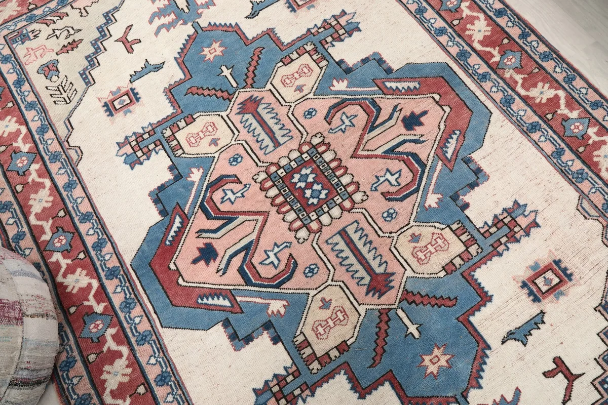 Overhead close-up of the rug's central geometric medallion in blue, pink, and ivory tones.