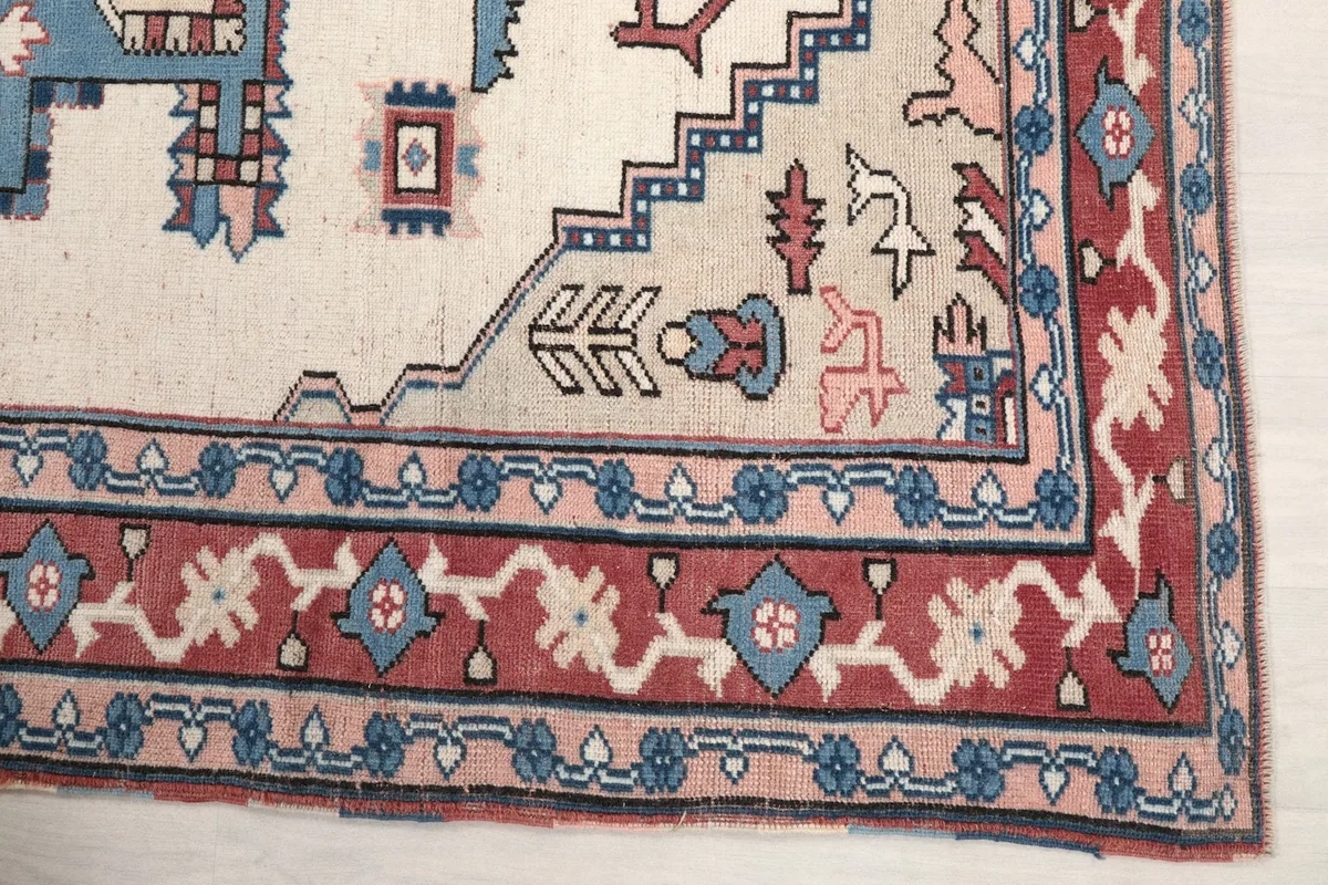Detail of the rug's red and blue patterned border, showcasing the intricate hand-knotted craftsmanship.