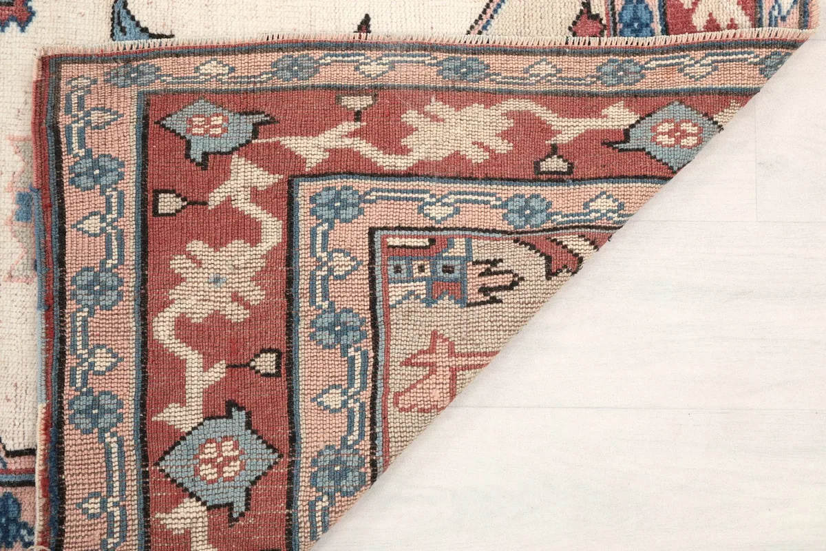 Underside view of a rug corner, showing the cotton foundation and hand-knotted backing.