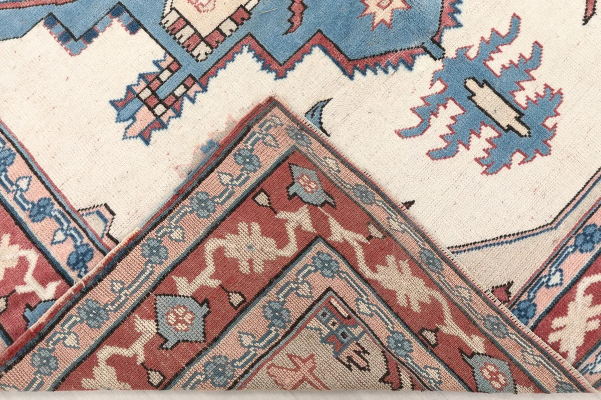 Folded corner of the rug, revealing the wool pile and the construction of the border.