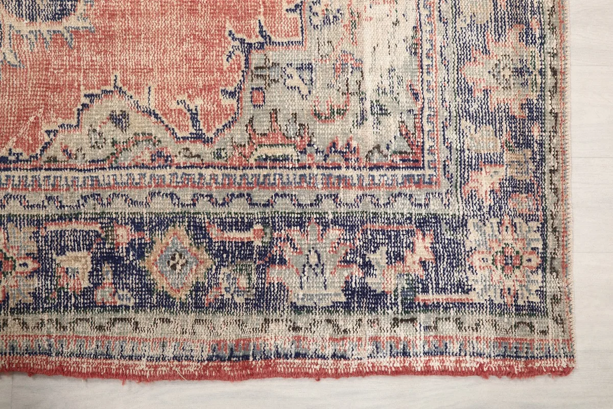 Detailed view of the navy and beige geometric border pattern of the vintage rug