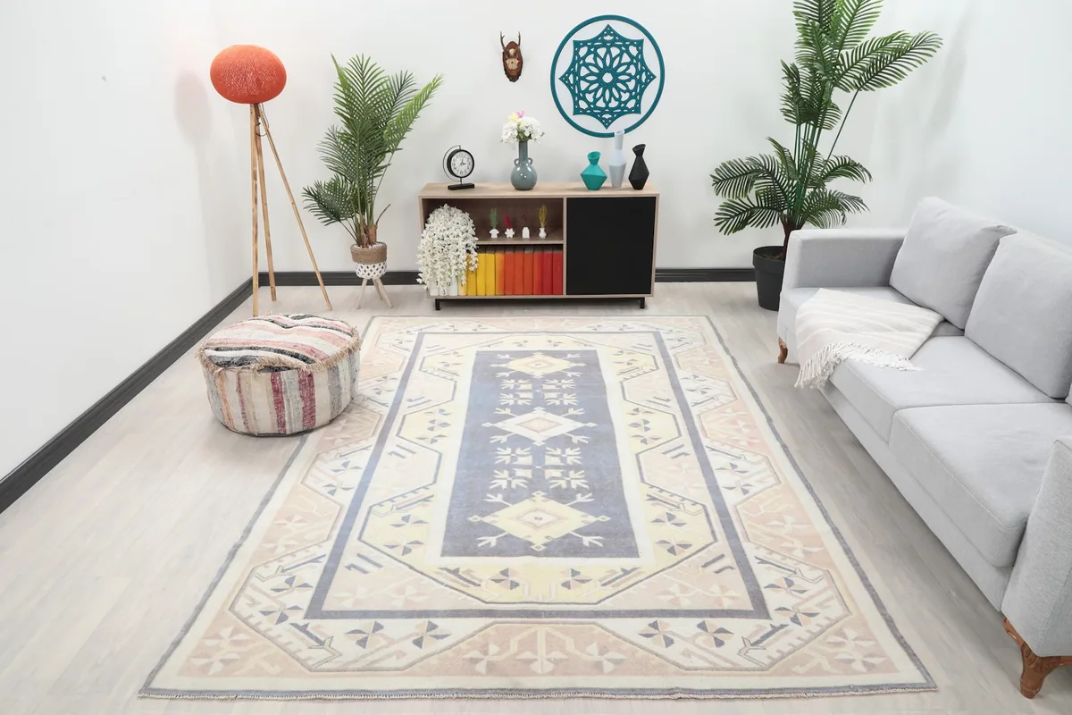 Vintage Anatolian rug with blue and beige tones placed in a modern living room setting with a gray sofa.