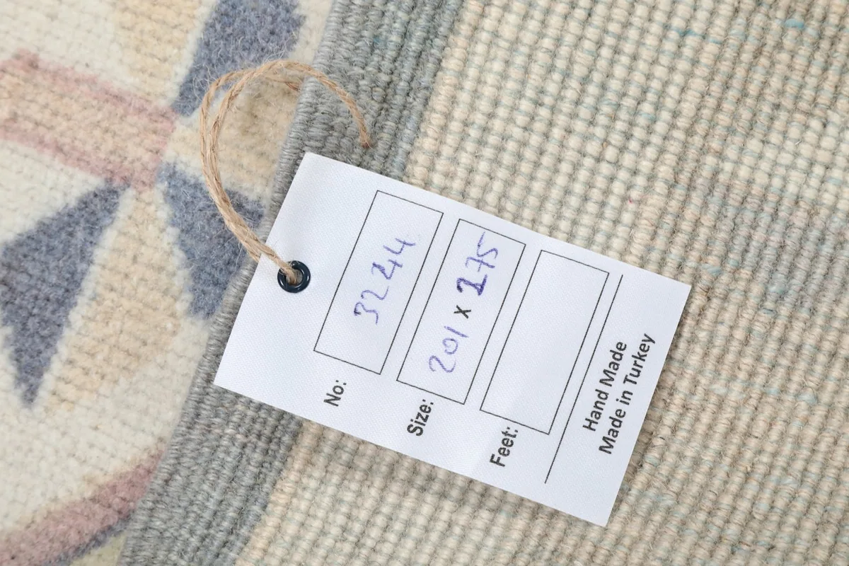 Close-up of the rug's tag, indicating it is hand-made in Turkey with dimensions 201 x 275 cm.