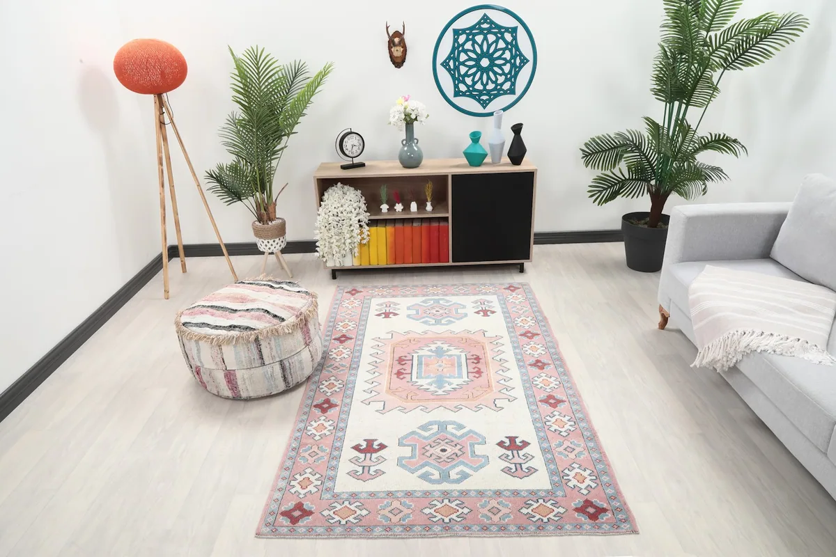 Cream and pink tribal rug placed in a modern living room setting with a light gray couch