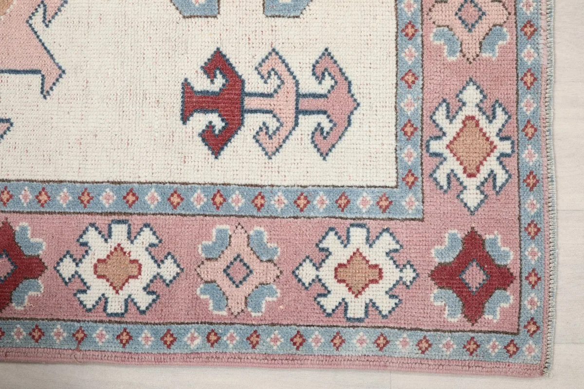 Close-up of the pink border with blue and red geometric details on the vintage rug