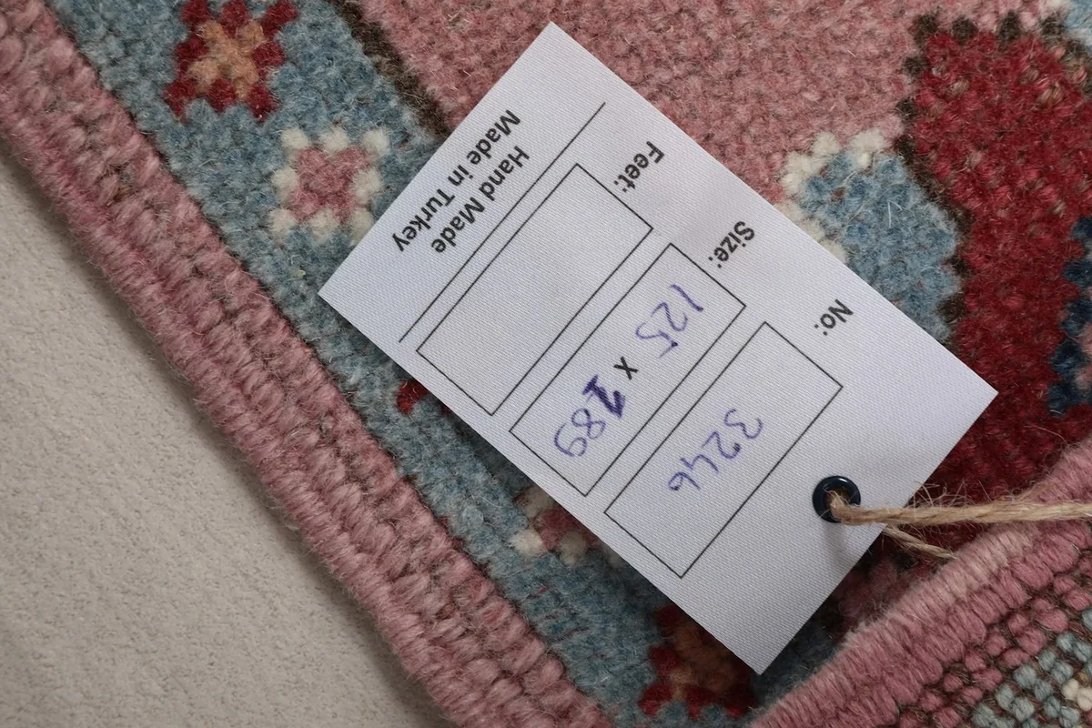 Close-up of the product tag displaying the rug's size in cm and hand-made origin