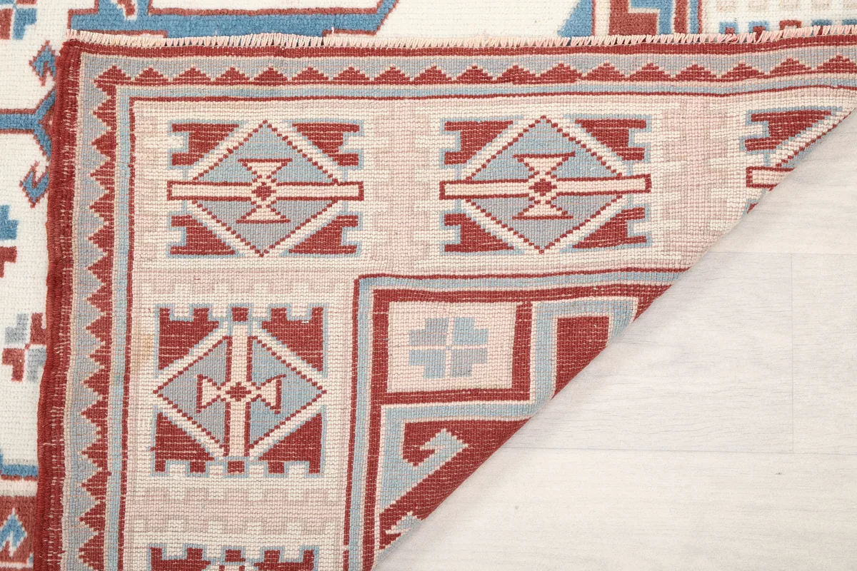 Back of a folded corner of the Rust Ivory Geometric Anatolian Rug, showing the hand-knotted construction