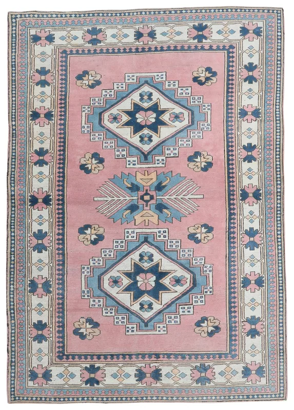 Full overhead view of the rose, blue, and ivory vintage Anatolian geometric medallion rug on a white background.