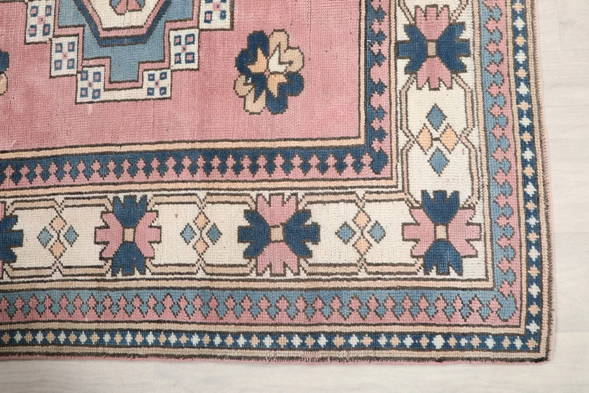 Detailed view of the rug's border design, featuring navy, rose, and ivory geometric patterns.