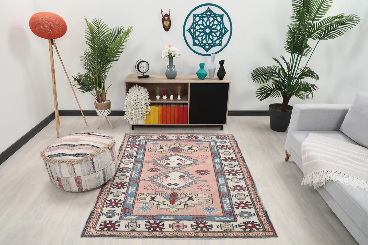 Vintage pink Anatolian rug displayed in a living room setting with a light couch and plants