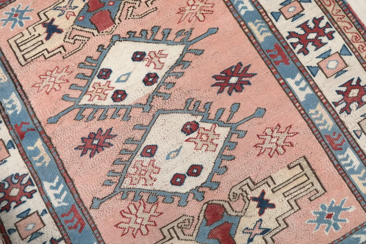 Detailed view of the central pink field and ivory geometric medallions with blue and red accents