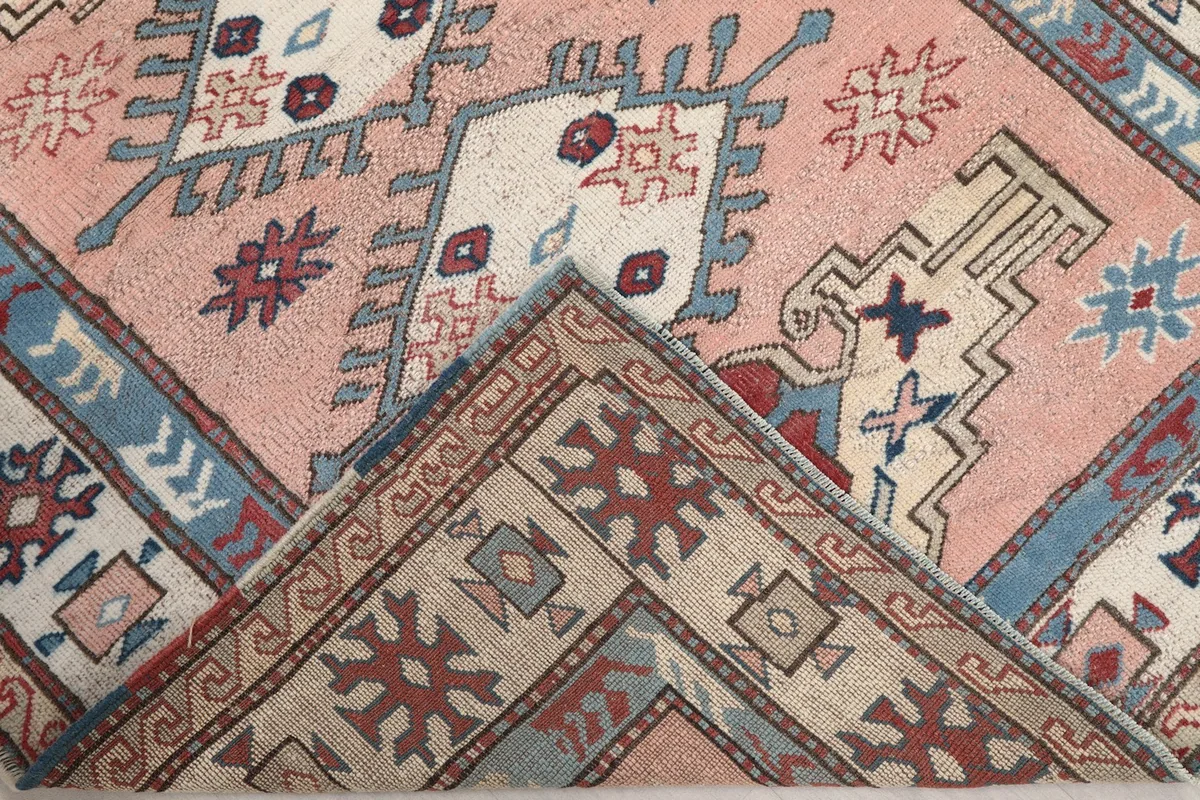 View of a folded corner of the rug, revealing the wool pile and cotton foundation