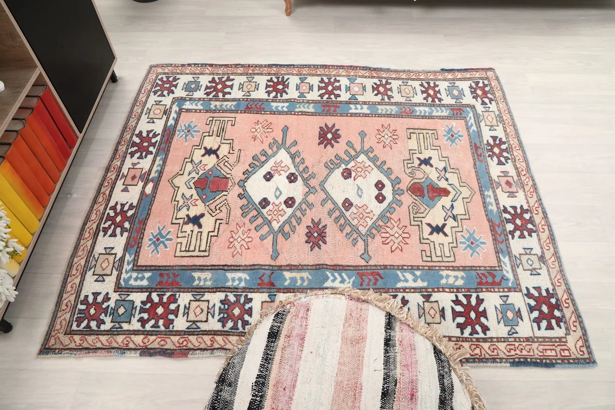 Full overhead view of the pink vintage rug in the room, with a decorative pouf partially on it