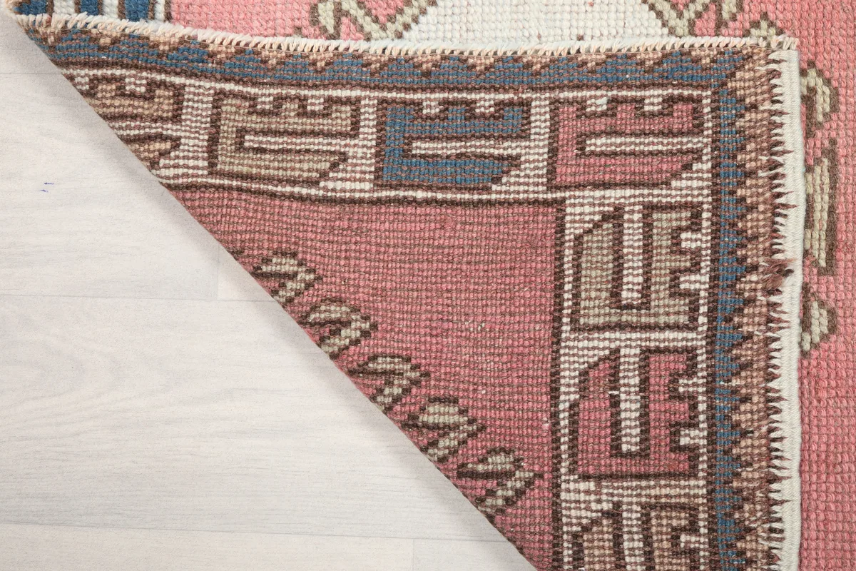 Rose Geometric Star Rug, another view of the corner folded back, showing the reverse side of the hand-knotted wool pile.