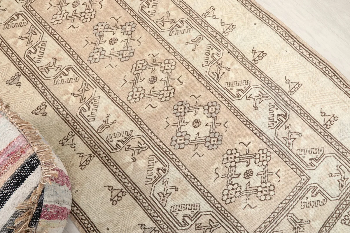 Oblique view of the rug's central design and outer borders, showing the beige and ivory tones.