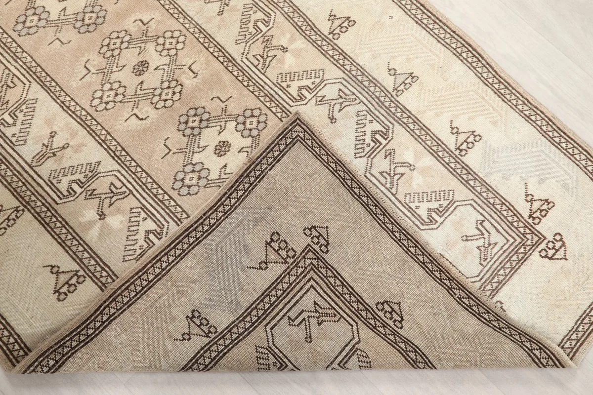 View of the rug folded to show the back and foundation, highlighting its hand-knotted construction.