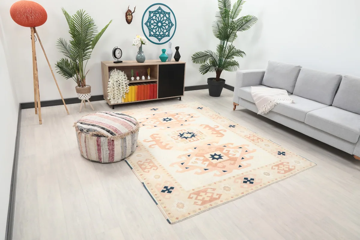 Angled view of the ivory and rust geometric rug in a modern living space with a striped pouf