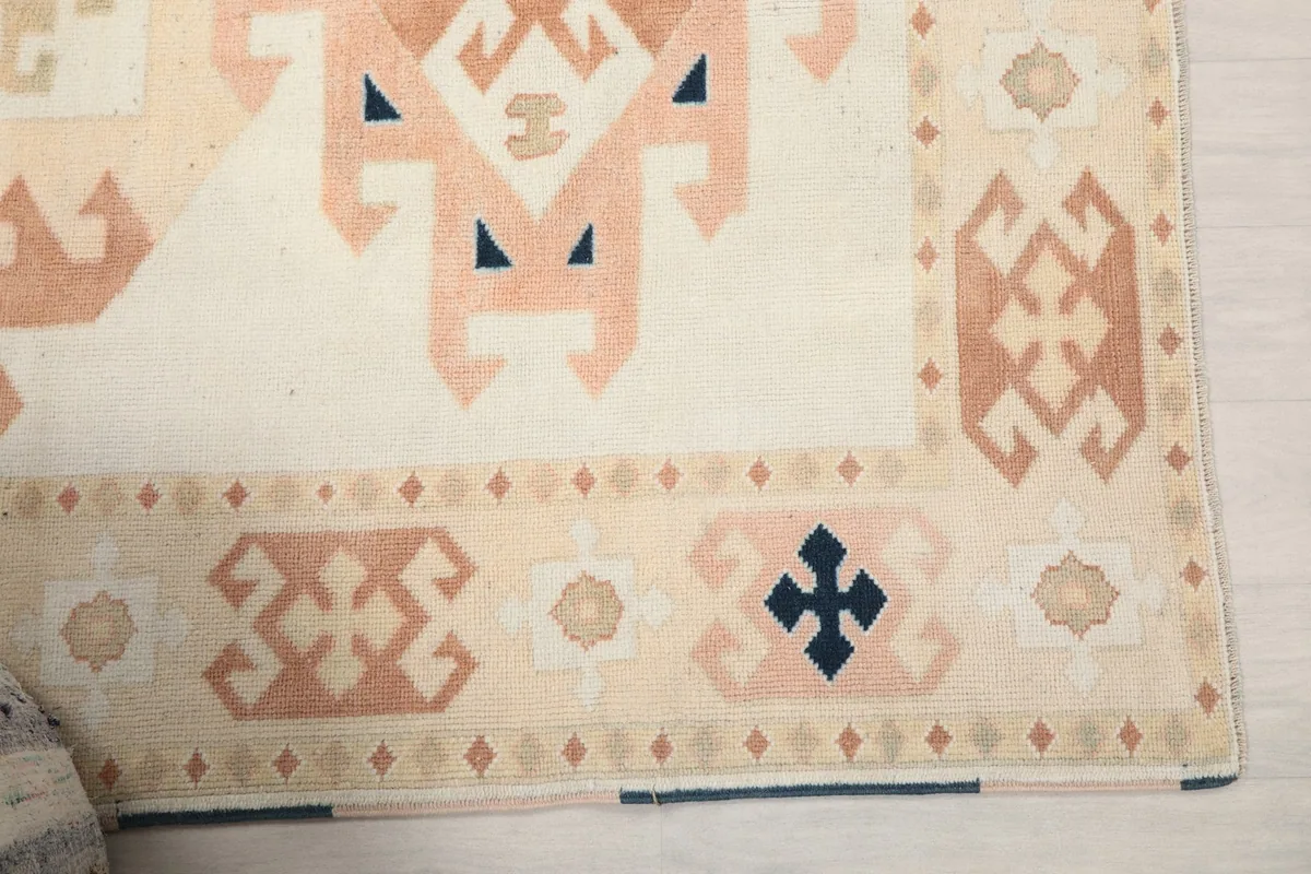 Detail of the rug's beige border with small geometric patterns and a navy corner motif