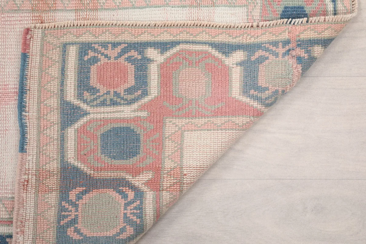 Close-up of the rug's folded edge, showing the back of the hand-knotted wool construction