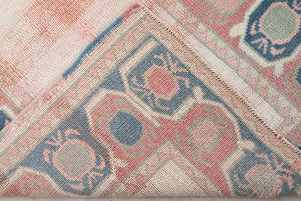 Folded corner of the rug revealing the cotton foundation and reverse side of the hand-knotting