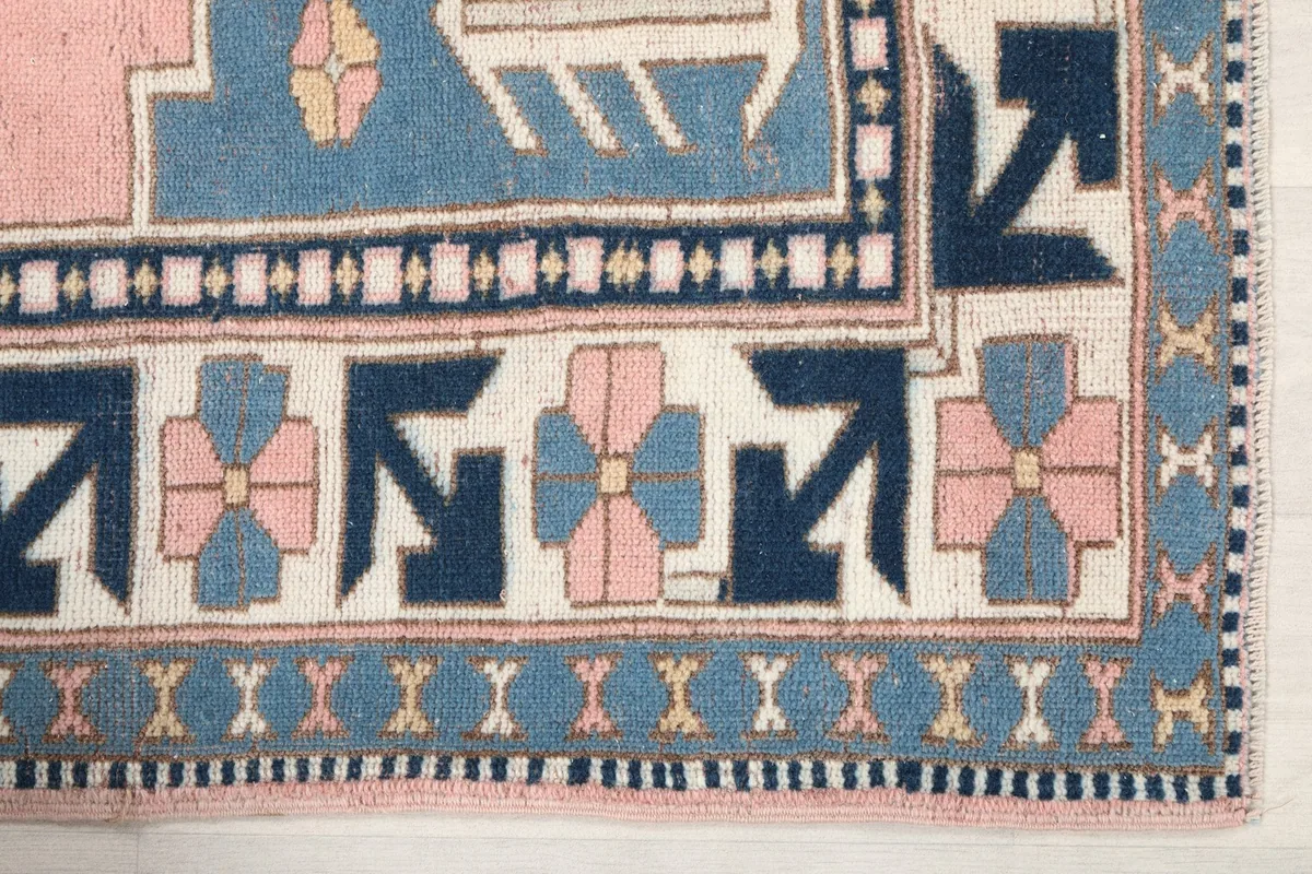 Detailed view of the corner border with navy and pink floral-like motifs on the rug