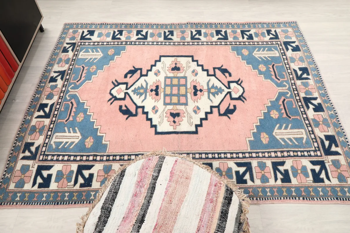Full overhead view of the vintage area rug with an ottoman in the foreground