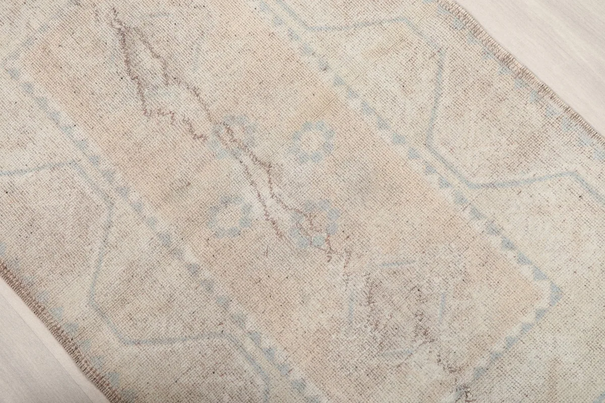 Overhead angle view of the beige rug's center, showing the softened blue patterns and natural color variations