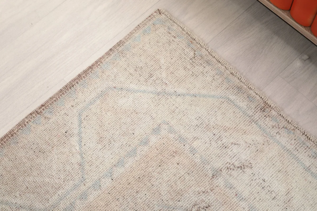 Corner detail of the rug, showing the faded blue border pattern and the edge finish