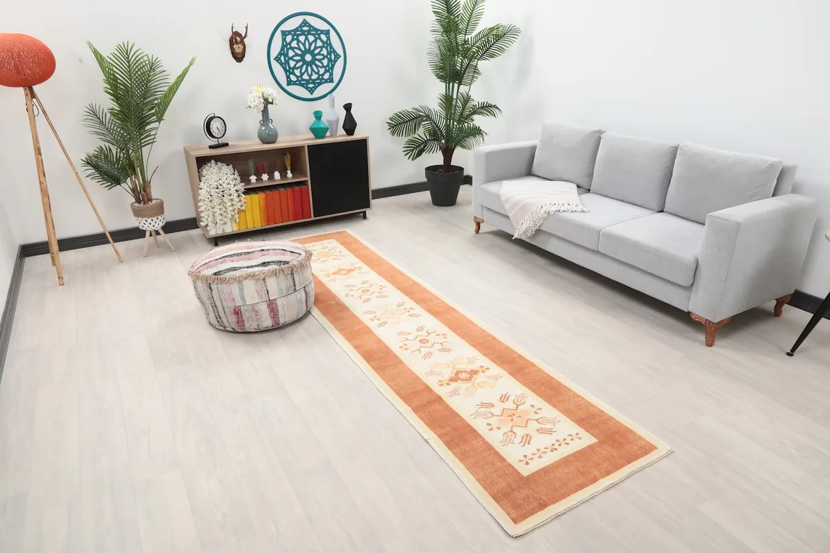 Angle view of the rust and ivory runner rug in a room, highlighting its placement next to a sofa