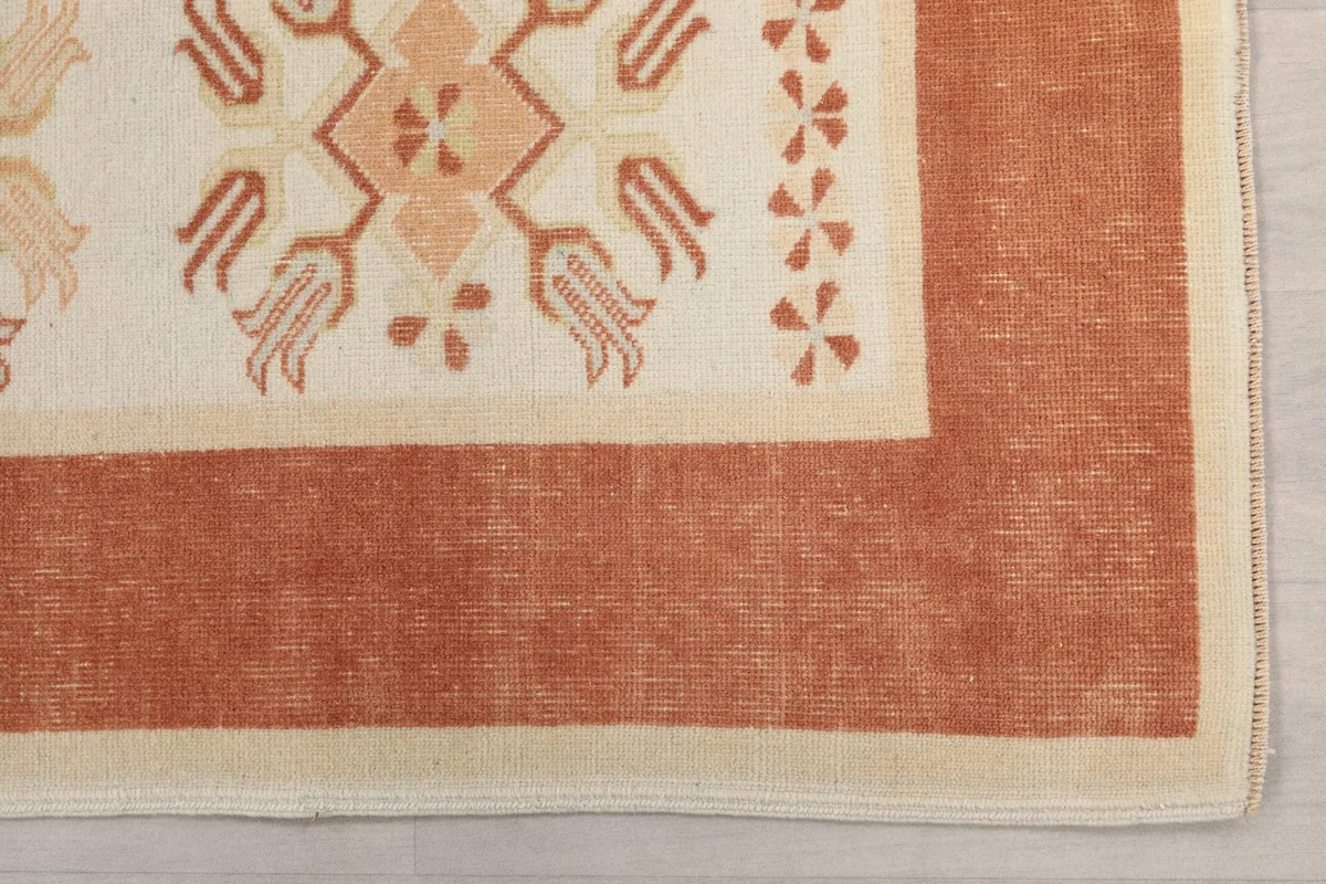 Detail of the rust border and a corner of the ivory field with small geometric patterns