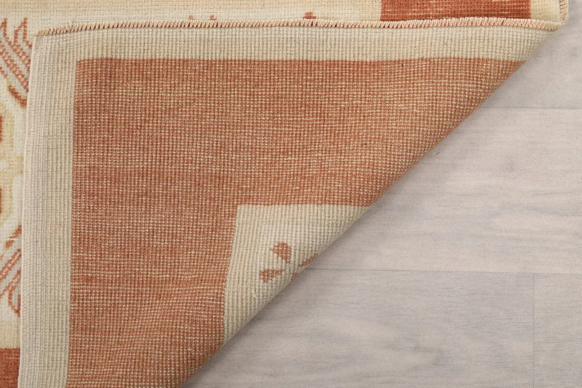 Underside view of the rug's corner, showing the hand-knotted cotton foundation