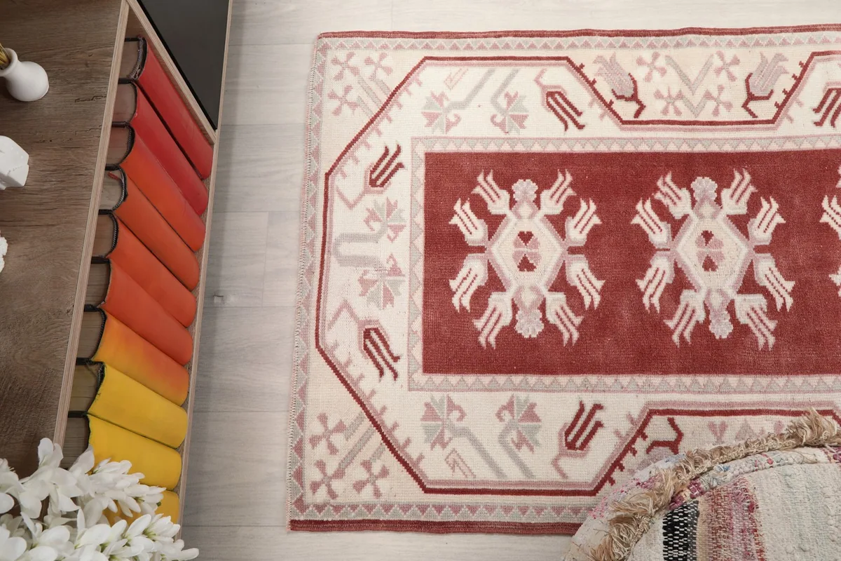 Angled view of the rug's design, showing the contrast between the red field and ivory border