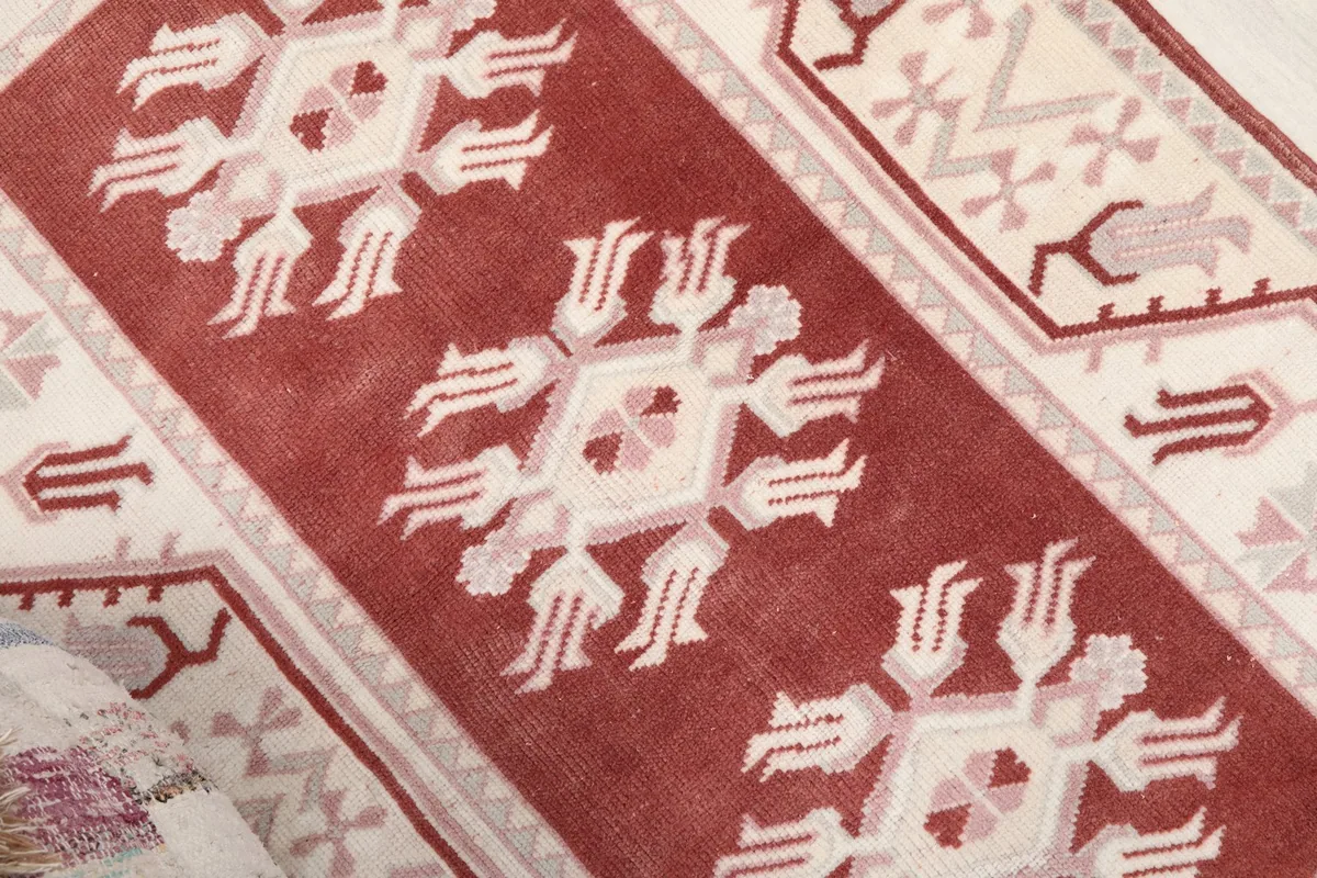 Close-up of the central red field and one of the ivory and pink geometric motifs