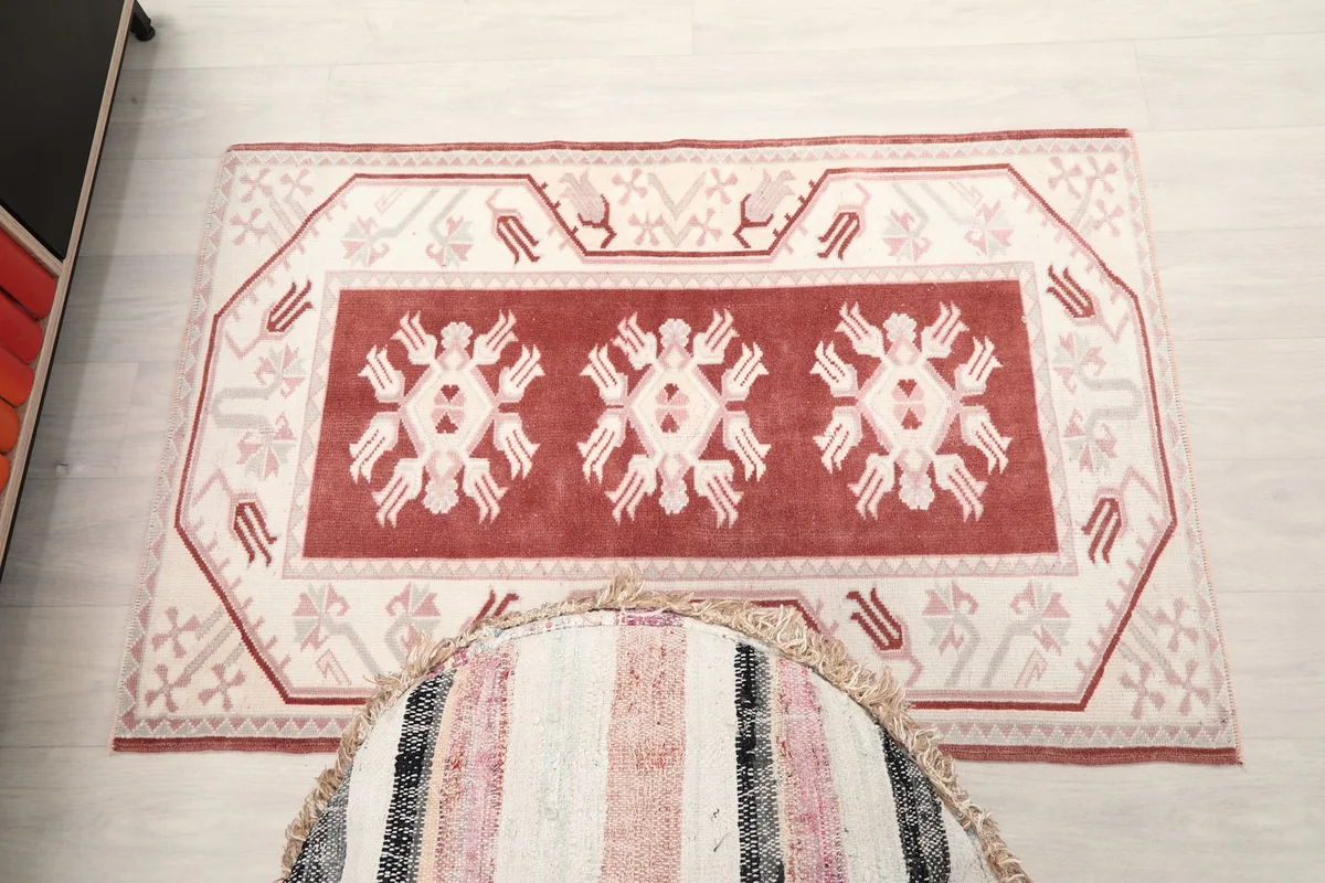 Overhead shot of the rug on a light floor, positioned next to a striped ottoman